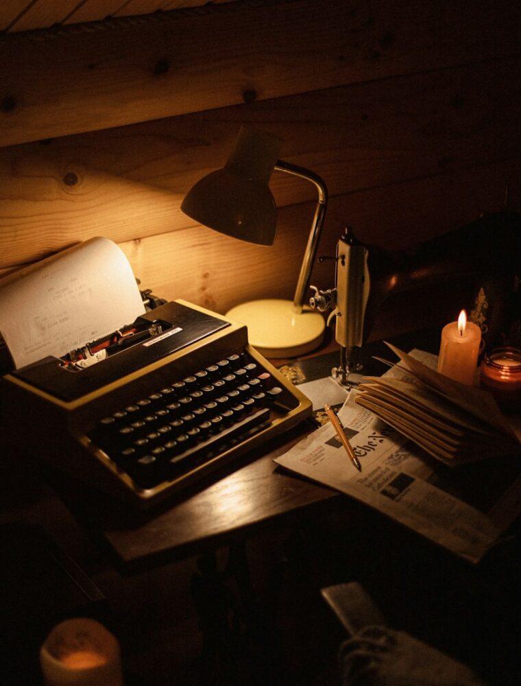 A typewriter on a writer’s desk by lamplight
